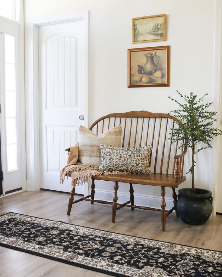 a wooden bench sitting in the middle of a living room next to a rug on top of a hard wood floor