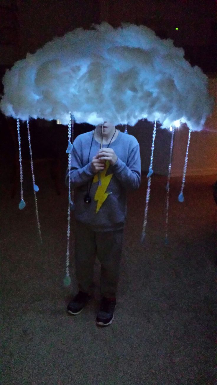 a man standing under a cloud with a lightning bolt on it's head and holding a cell phone in his hand