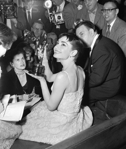 an old black and white photo of a woman holding up her oscar award