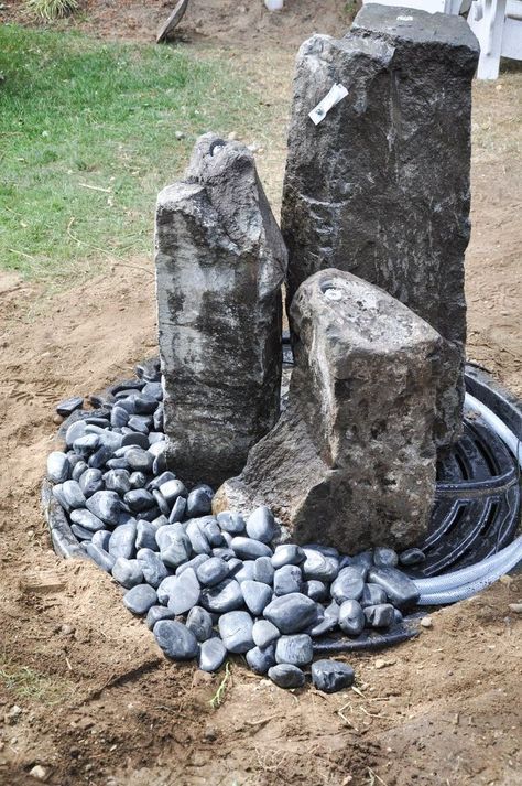 two large rocks sitting on top of a pile of rocks next to a water hose