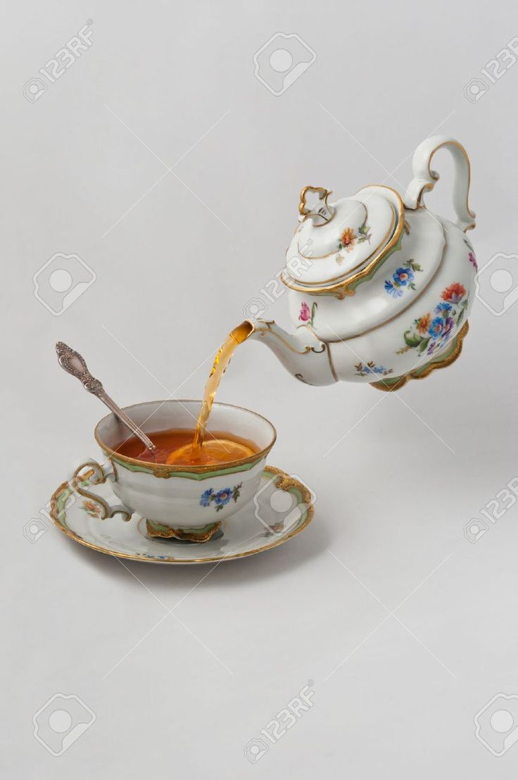 tea being poured into a cup with saucer and spoon on the side, in front of a white background