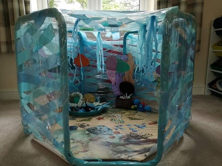 an inflatable play tent sits on the floor next to a window with curtains