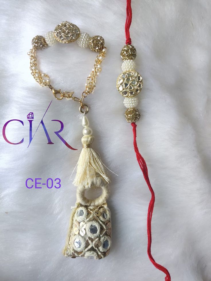 two necklaces are laying on a white furnishing and one has a tassel hanging from it