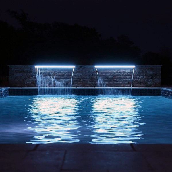 an outdoor swimming pool at night with lights reflecting off the water