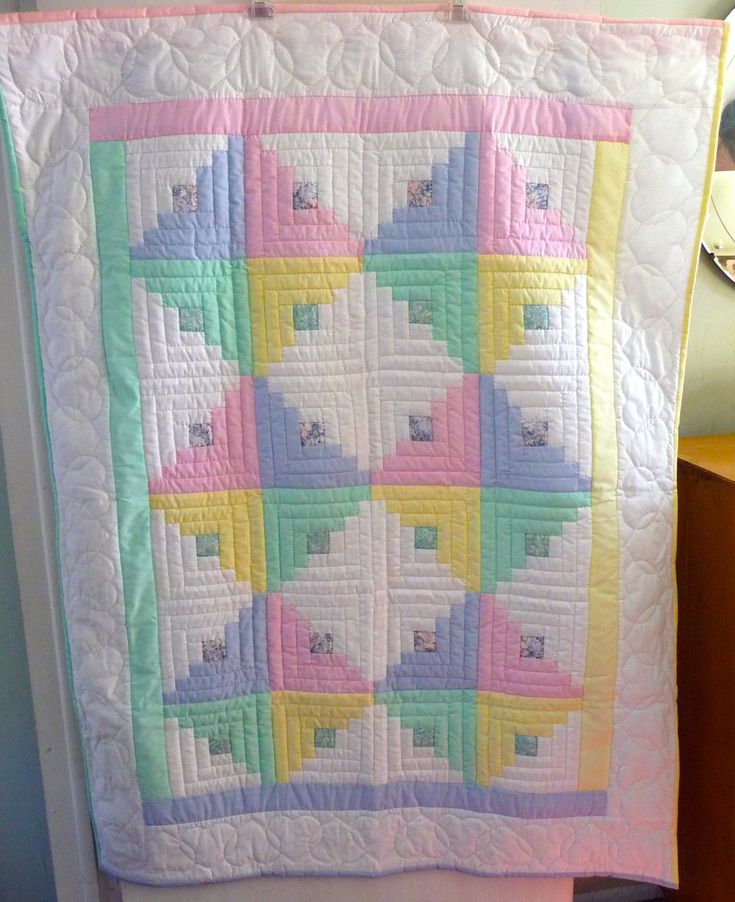 a colorful quilt hanging on the side of a wall