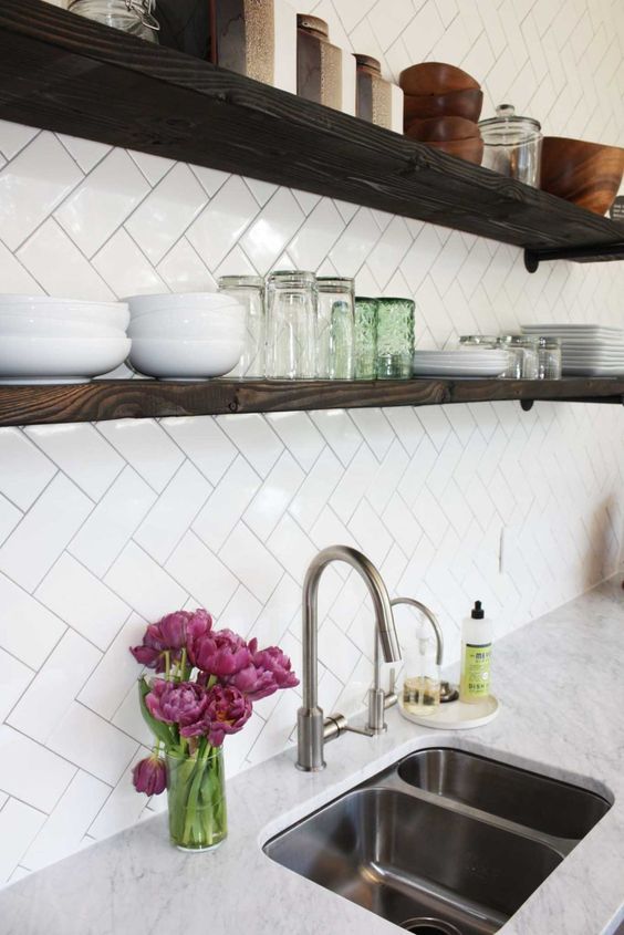 a kitchen with white counter tops and open shelving above the sink is filled with dishes