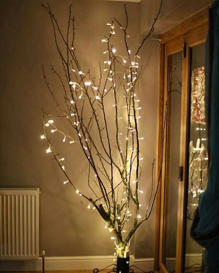 a lighted tree in the corner of a room with a radiator next to it