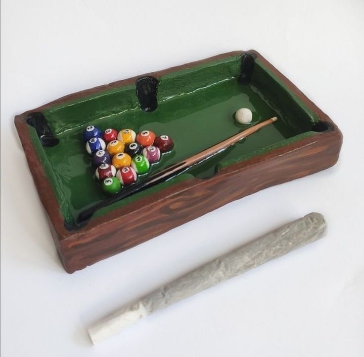 a pool table with billiards, cues and ball on it next to a knife