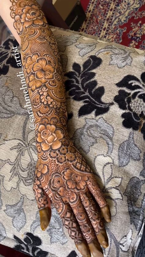 a woman's hand with henna tattoos on her arm and hands, showing the intricate