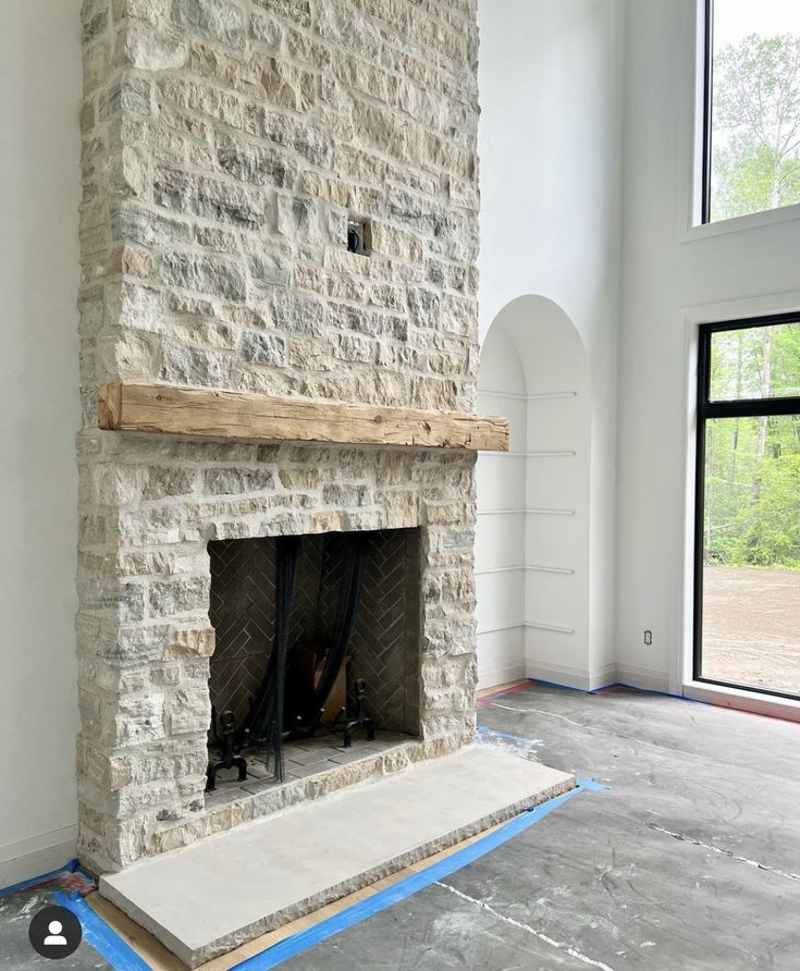 an empty room with a stone fireplace in the middle