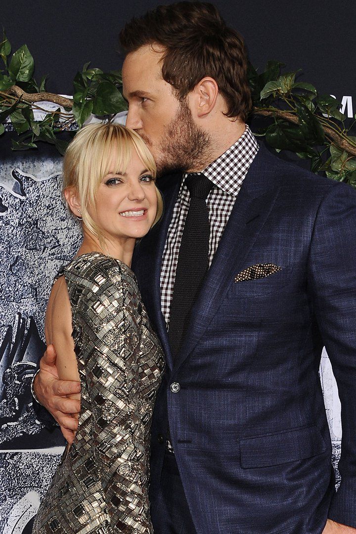 a man and woman kissing on the red carpet at an awards event with greenery around them