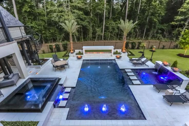 an outdoor swimming pool surrounded by lounge chairs and trees in the back yard, next to a fire pit