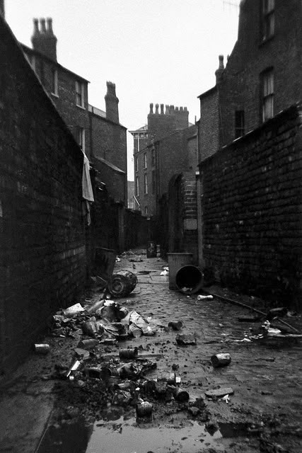 an alley way with trash on the ground and buildings in the backgrouns