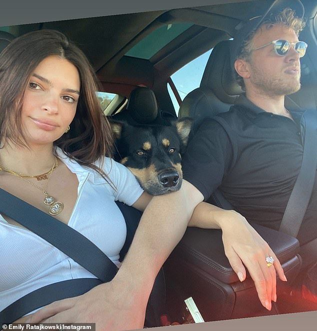 a man and woman sitting in the back seat of a car with a dog on their lap