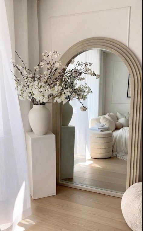 there is a vase with flowers in it and a mirror on the wall next to it