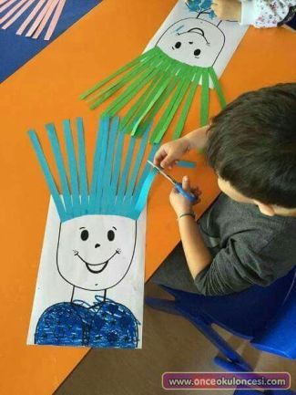 a young boy is drawing on paper with scissors