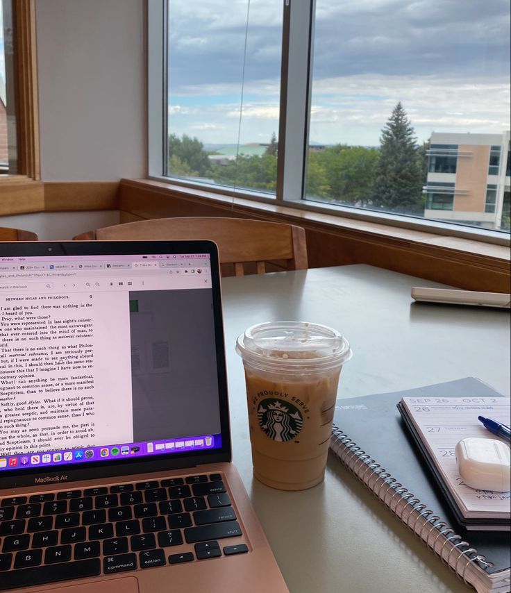 an open laptop computer sitting on top of a table next to a cup of coffee