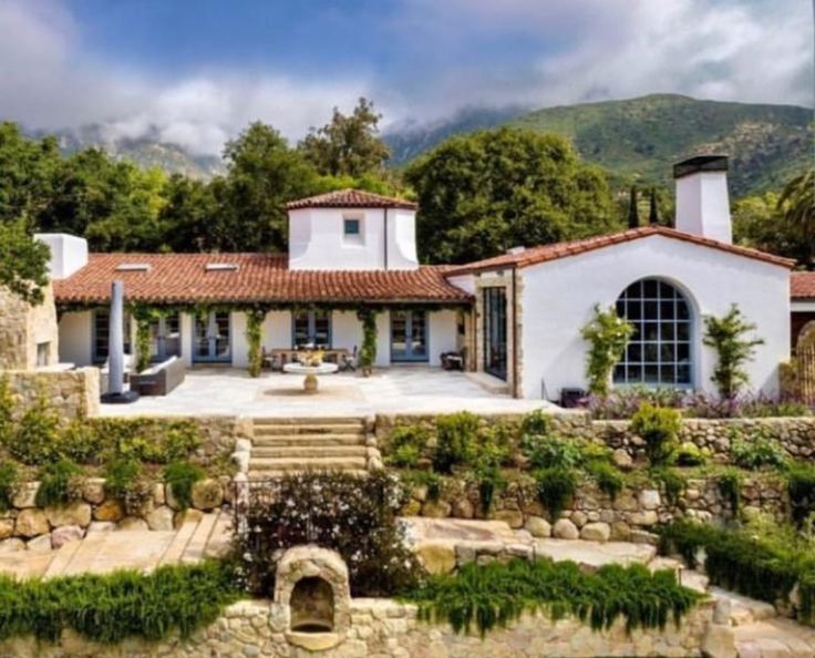 the house is surrounded by greenery and stone steps leading up to it's entrance