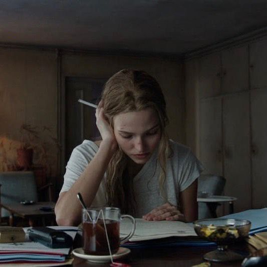 a woman sitting at a table with a book and pen in front of her head