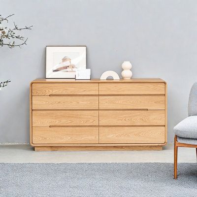 a grey chair sitting next to a wooden dresser on top of a carpeted floor