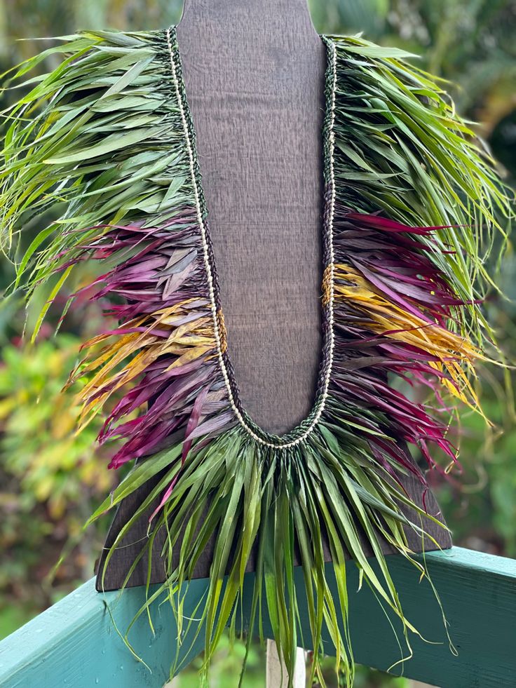 a necklace made out of grass and beads on top of a mannequin stand