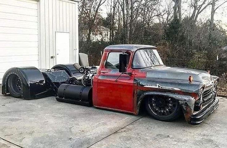 an old red truck parked in front of a garage