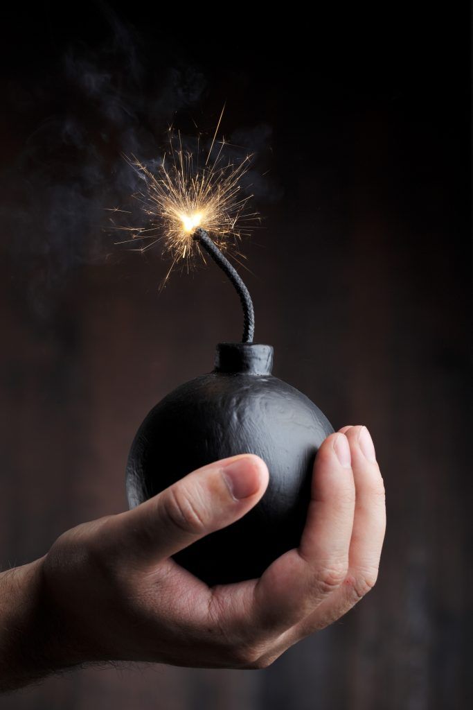 a hand holding a black bomb with a sparkler in it