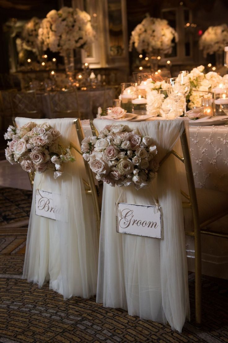 the chairs are decorated with white flowers and sashers for guests to sit down at