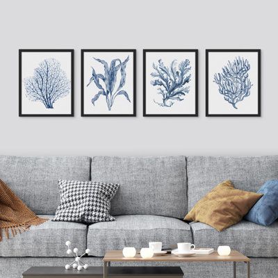 three blue and white seaweed prints hanging on the wall above a gray couch in a living room