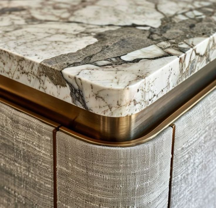 a close up view of a marble top on a bed with gold trimmings