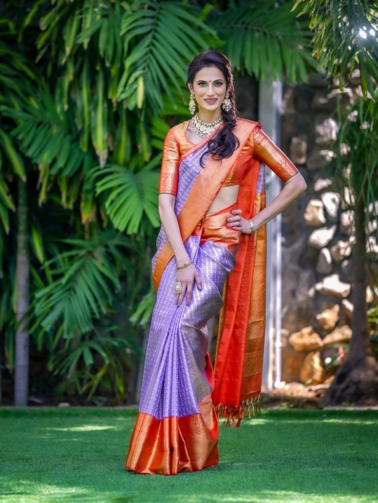 a beautiful woman in an orange and purple sari with her hands on her hips