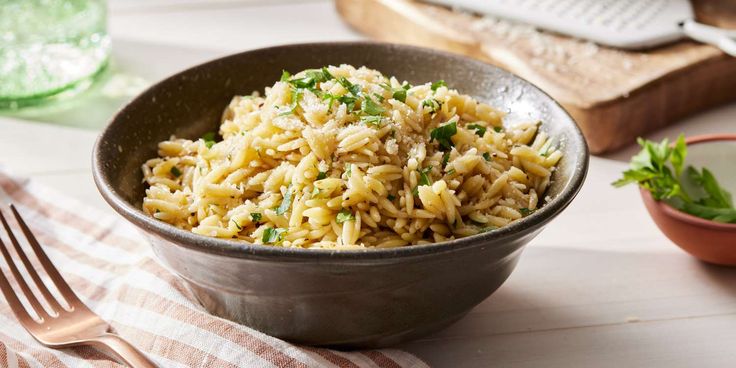 a bowl filled with rice sitting on top of a table next to a knife and fork