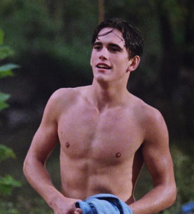 a shirtless young man holding a blue towel