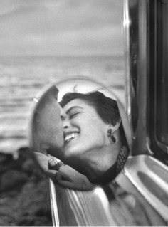 a black and white photo of a woman with her face close to the side of a train