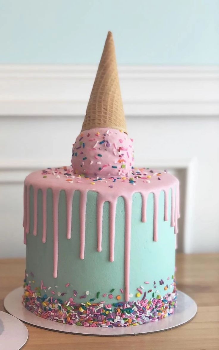 a birthday cake with sprinkles and an ice cream cone on top is sitting on a table