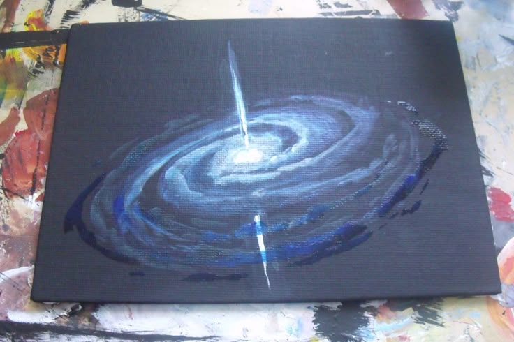 an abstract painting with blue swirls on black paper and white paint splattered over it