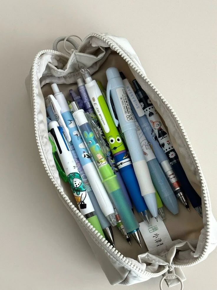 several pens and pencils in a white pouch