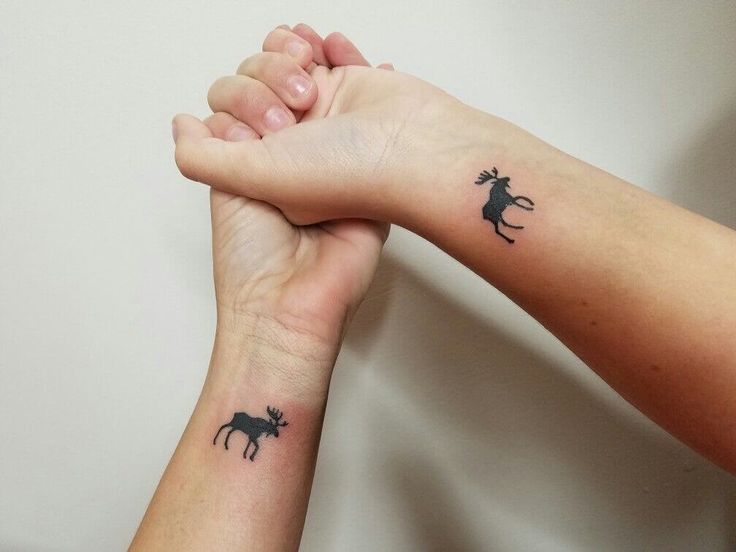 two people holding hands with small tattoos on their arms and one has a horse in the middle