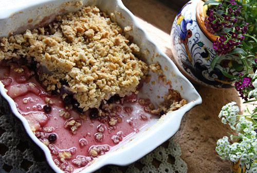 a bowl filled with fruit and crumbs next to a potted plant on a table