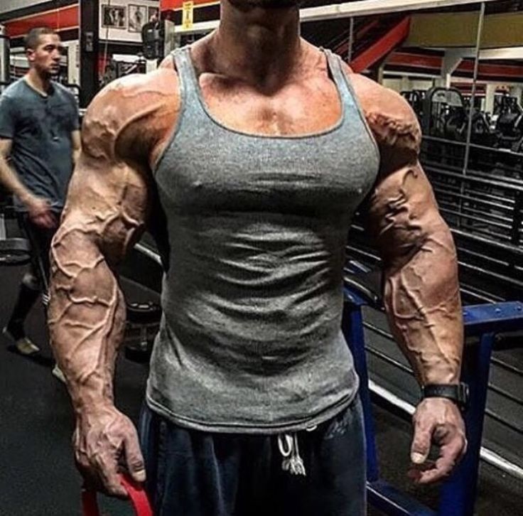 a man standing in a gym with his muscles ripped