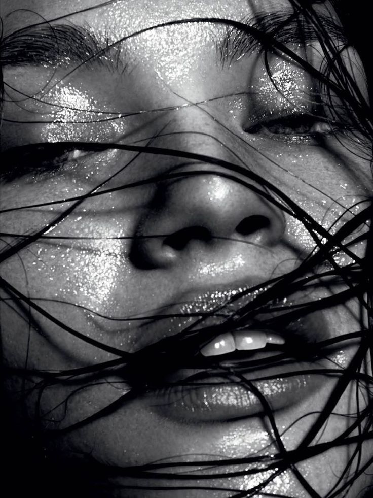 a black and white photo of a woman's face with hair blowing in the wind