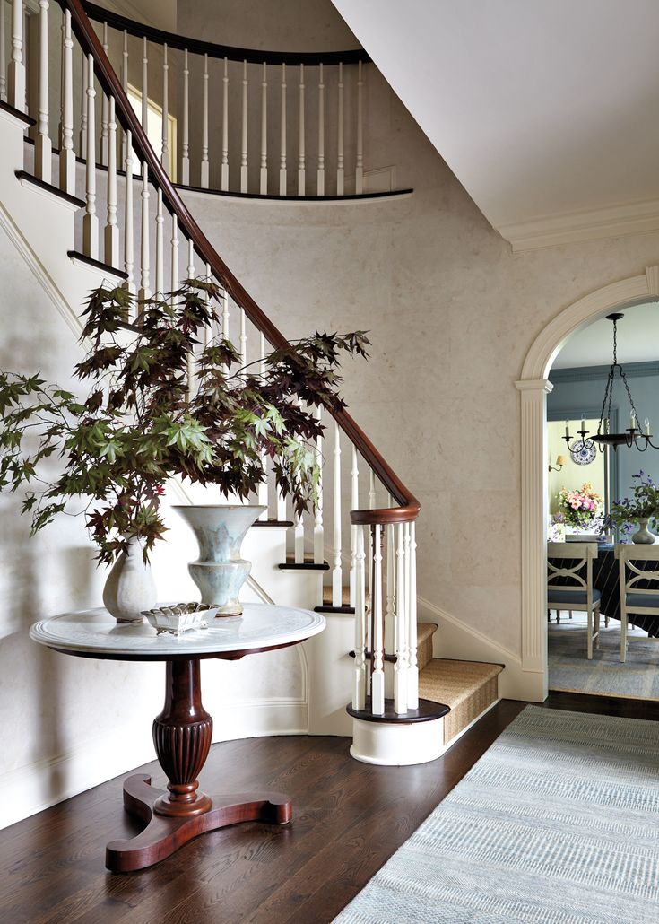 a table with two vases sitting on top of it next to a stair case