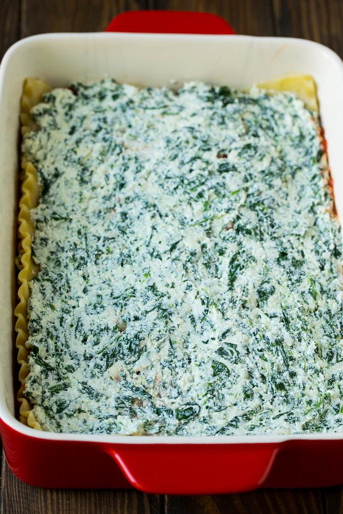 a casserole dish with spinach and cheese in a red pan on a wooden table