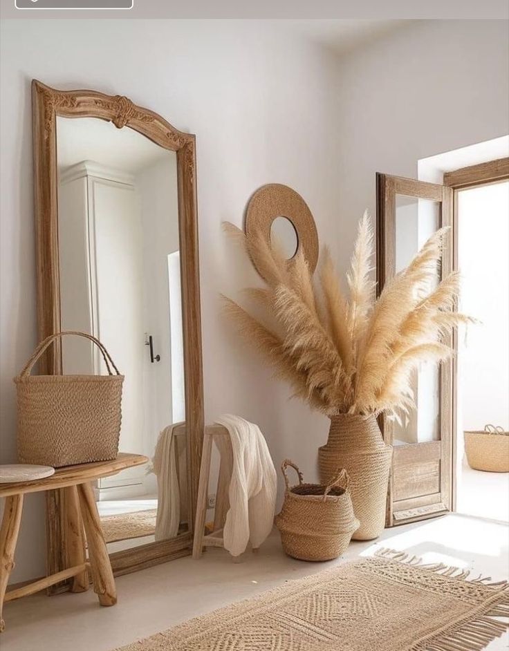 a large mirror sitting next to a vase filled with dry grass on top of a floor