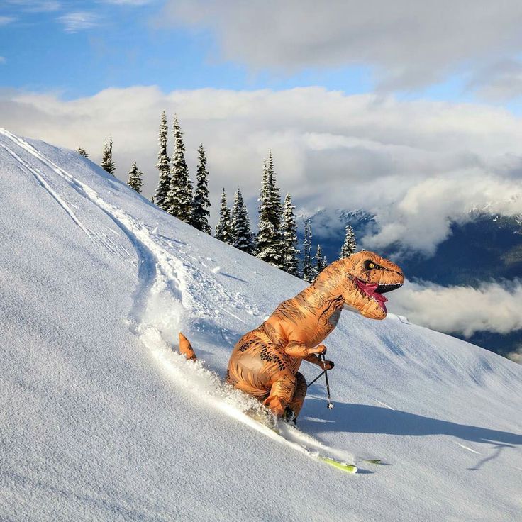 an inflatable dinosaur is skiing down a snowy hill