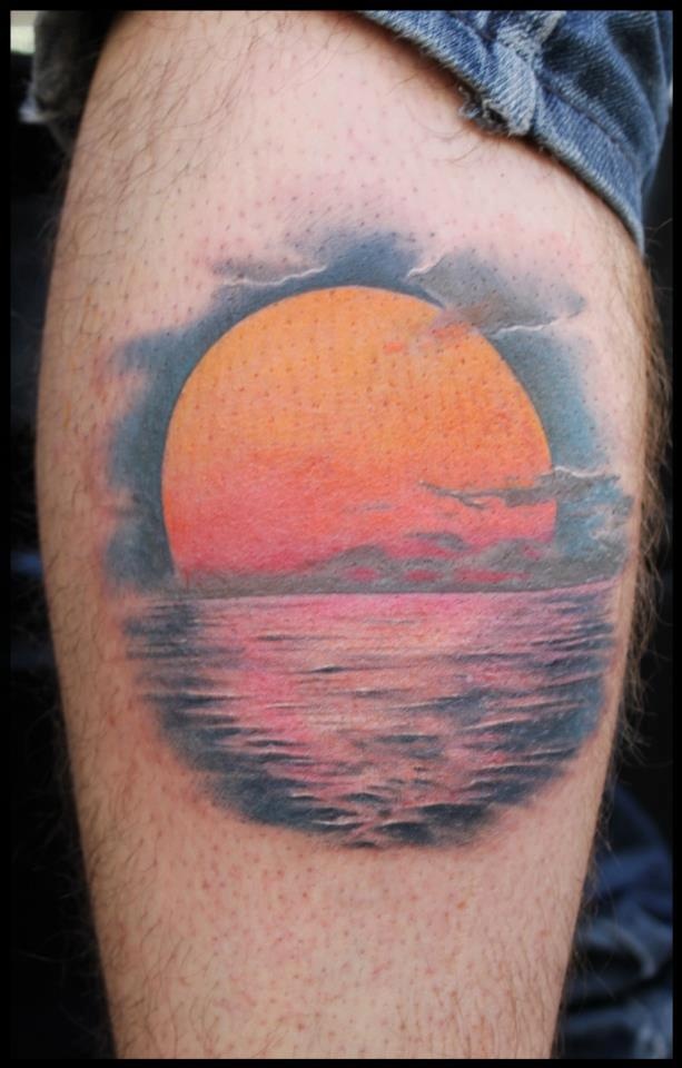 a man's arm with a sunset tattoo on the back of his left leg