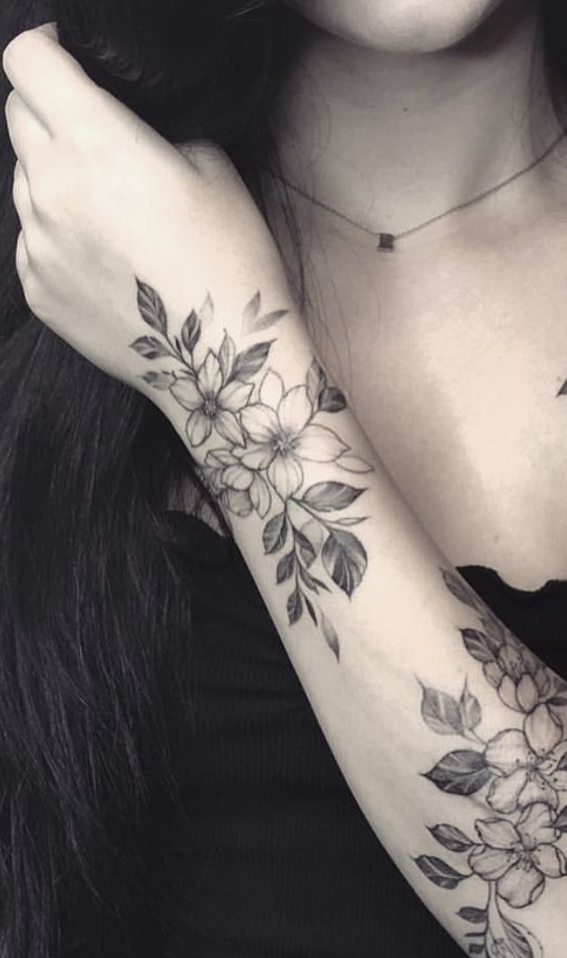 a woman's arm with flowers and leaves tattooed on her left arm, in black and white