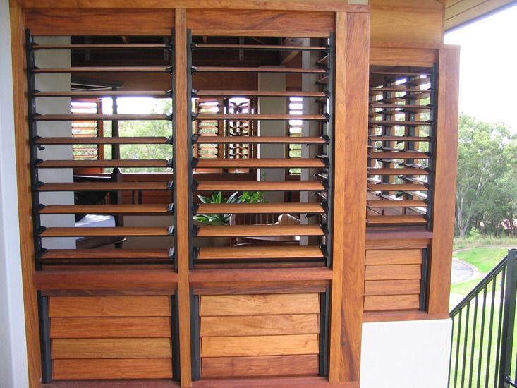 an open window with wooden slats on the side of it and black iron railing