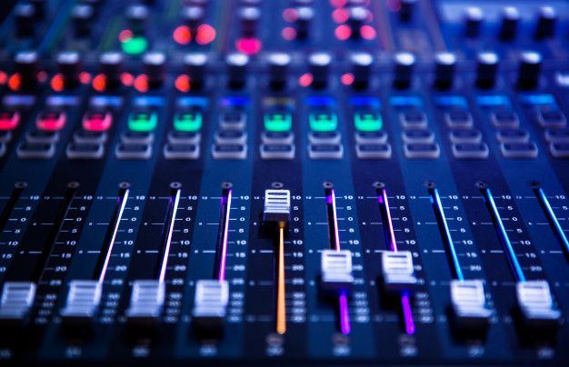 an audio mixing console with colorful lights in the background