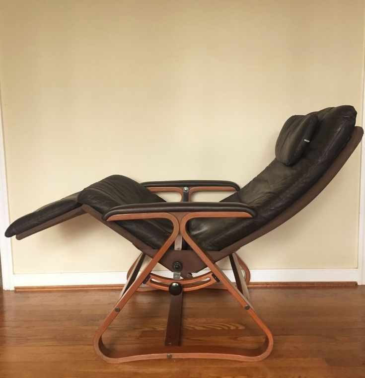 a reclining chair sitting on top of a hard wood floor next to a wall